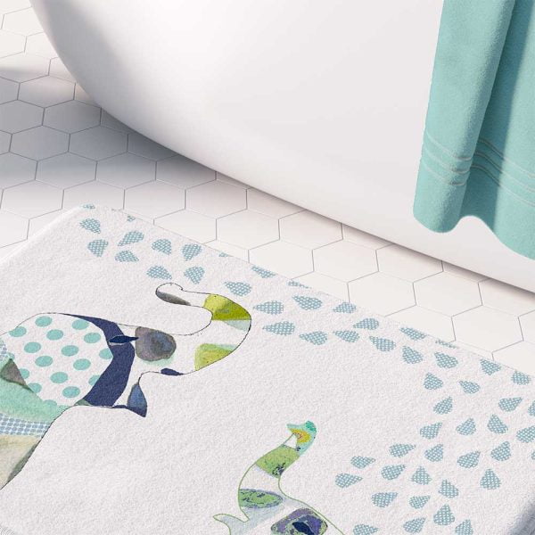 A white microfiber non slip bath mat for kids featuring a playful blue and green elephant print. Mold and mildew resistant, plush, soft, non-slip, machine washable, and quick drying.