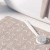 Beige non-slip bath mat featuring white trevally fish design."