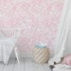 Soft pink watercolor leaves wallpaper in a baby nursery, creating a calming and cozy atmosphere